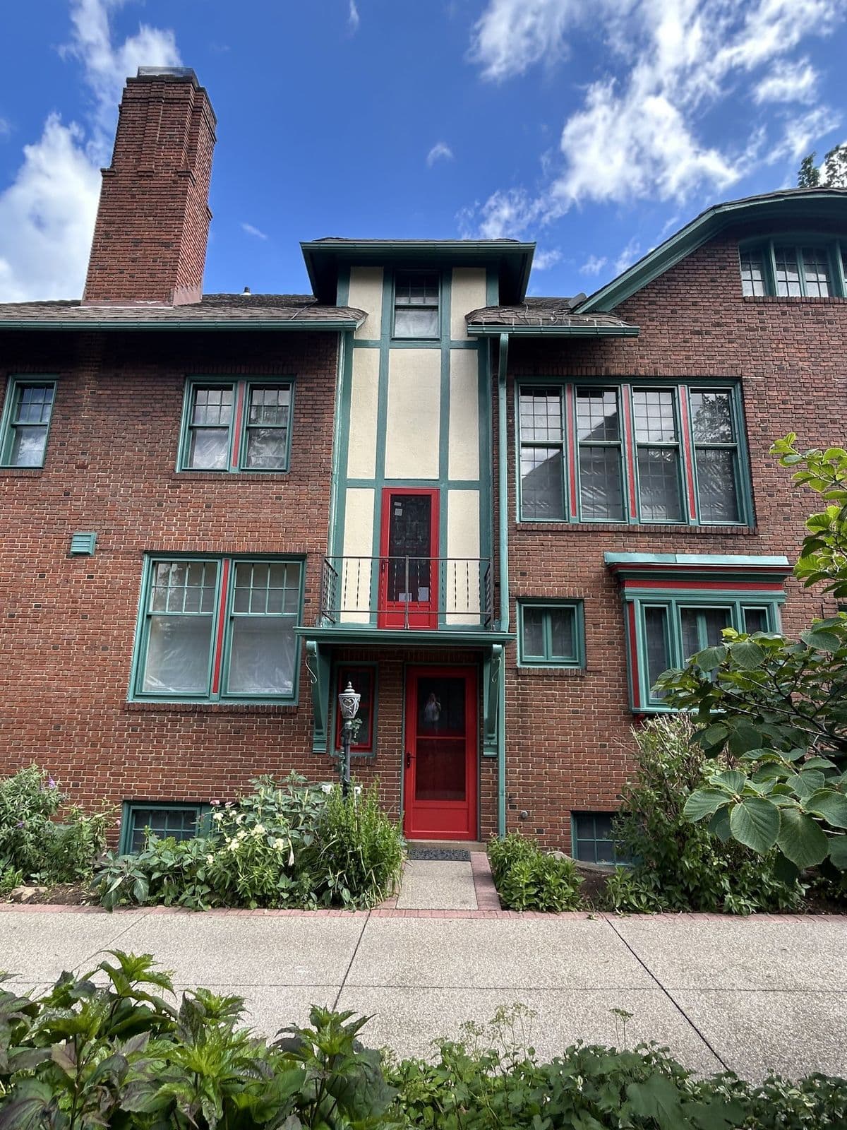 Restored balcony with cream stucco, teal timbers, and red doors in Cleveland Heights