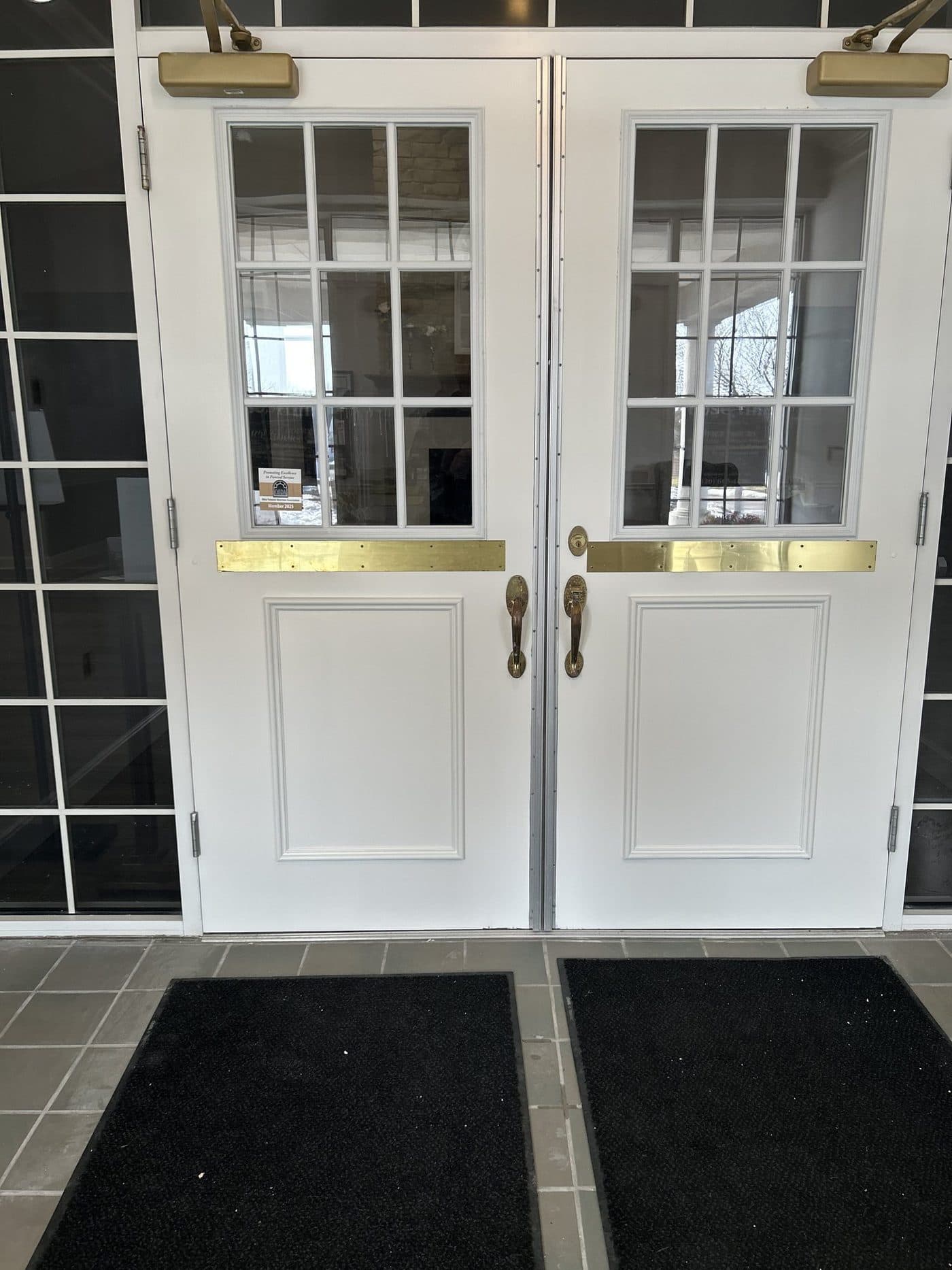 Freshly painted white commercial entry doors with brass hardware by Cavelli Painting