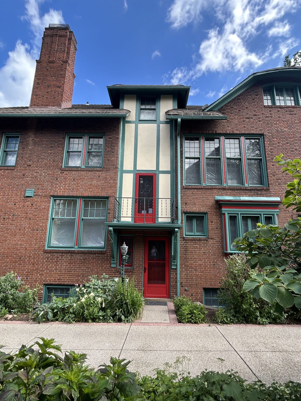 Restored balcony with cream stucco, teal timbers, and red doors in Cleveland Heights