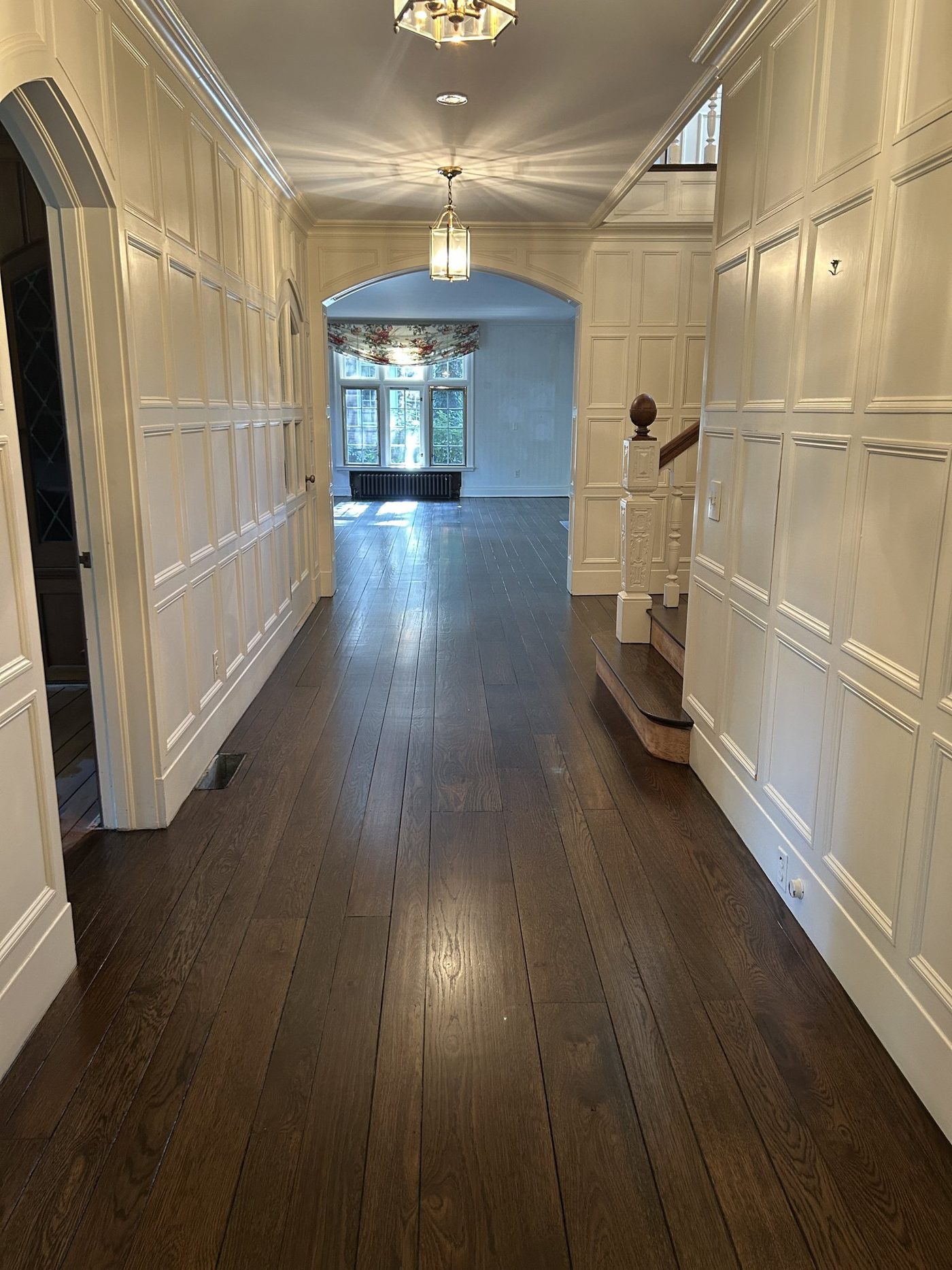 High-end interior painting — white paneled hallway with refinished dark floors in a Tudor home